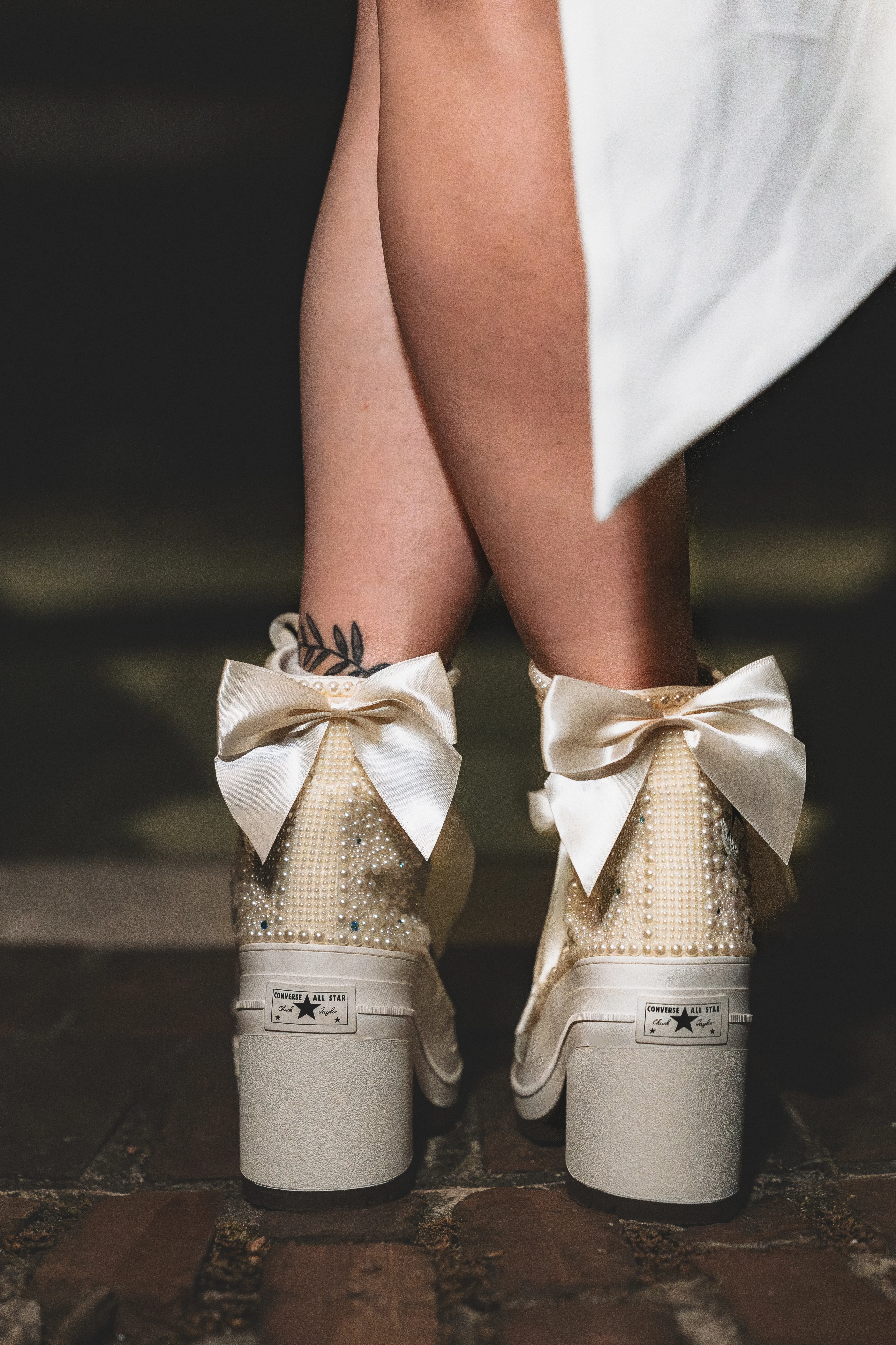 Back of custom bridal sneakers with satin bows and pearl details.