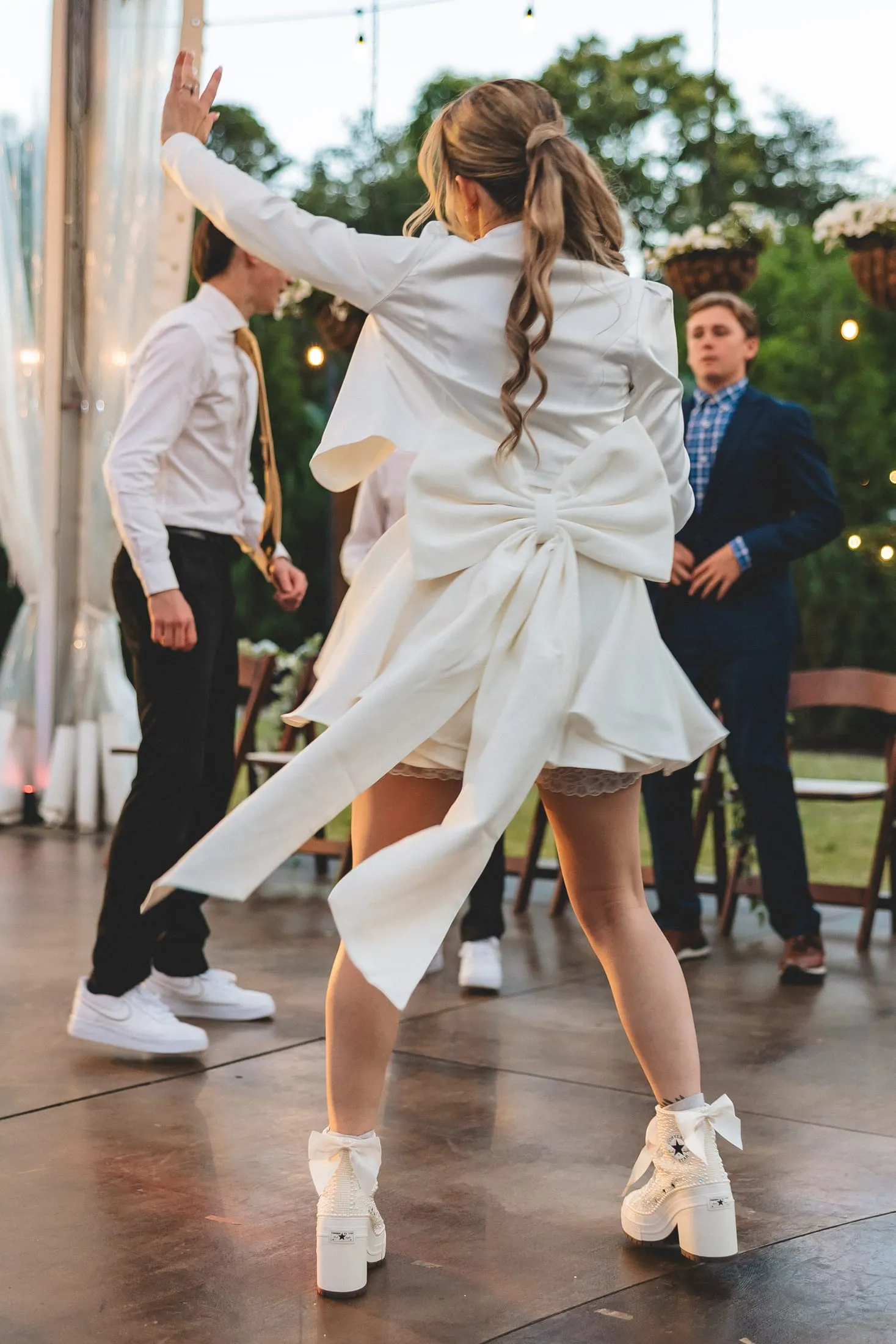 Bride standing in custom ivory Converse bridal sneakers.